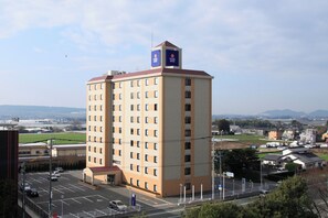 Ein mehrstöckiges Hotel mit einer auffälligen Beschilderung auf dem Dach, einem Parkplatz im Vordergrund und Blick auf die Umgebung.