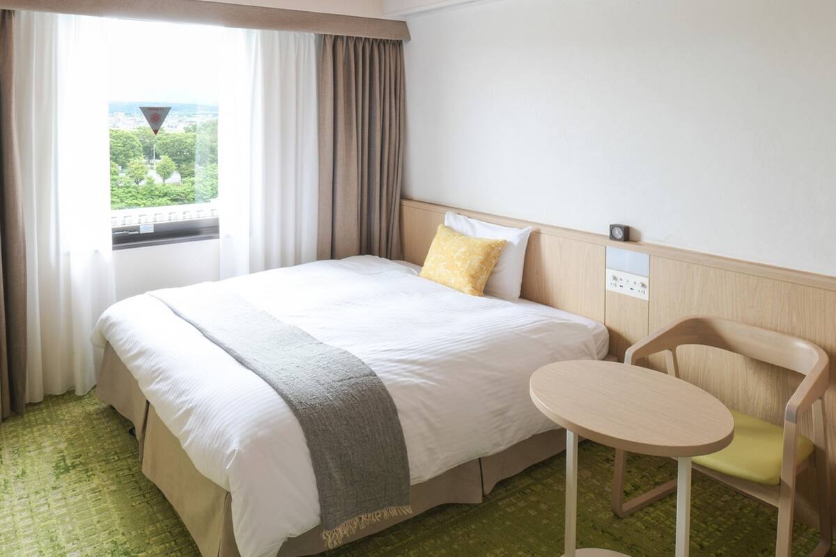 Una habitación de hotel con una cama, una mesita y una silla.