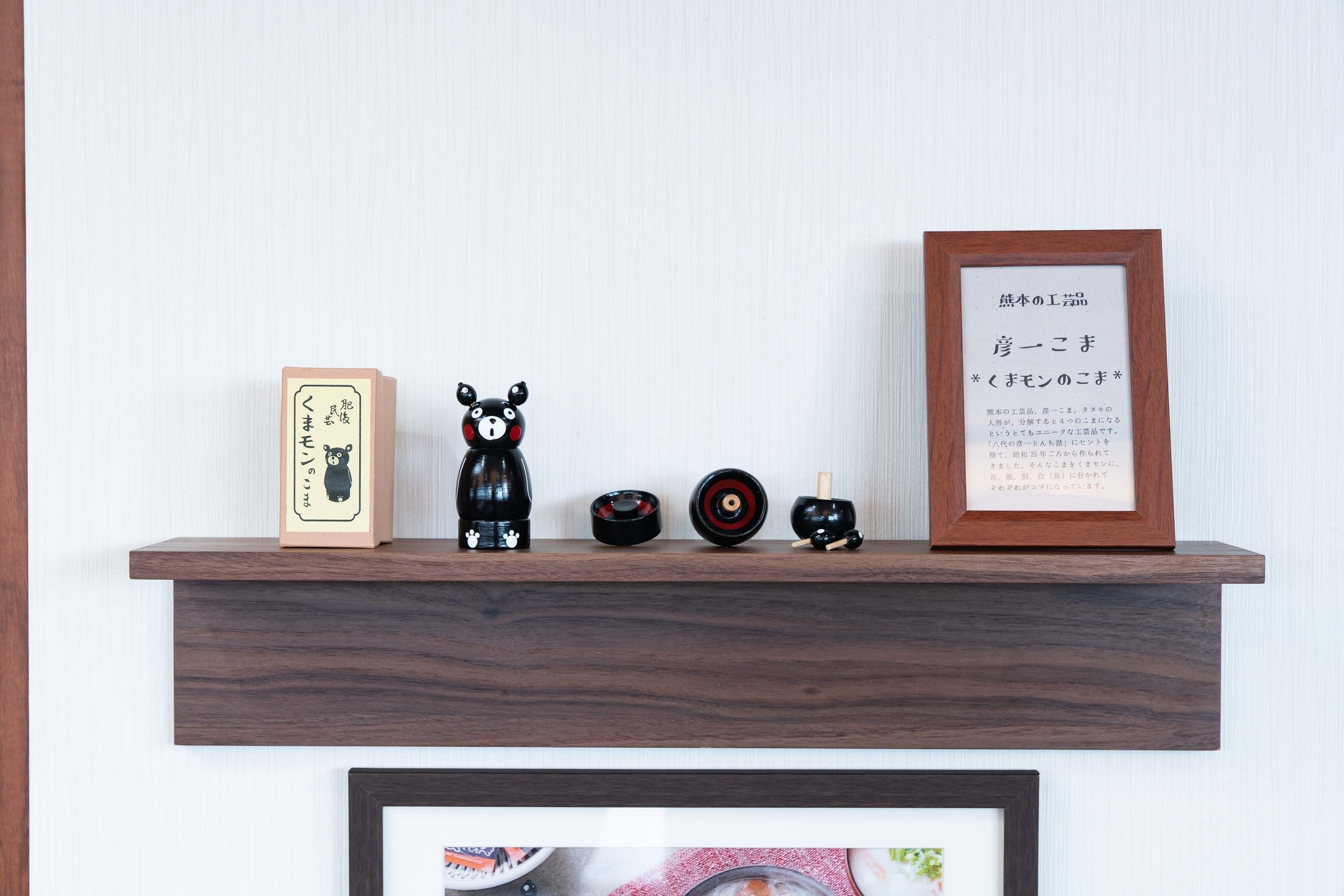 A wooden shelf with various items including a framed certificate, a black bear figurine, a small black bowl, and a wooden box.