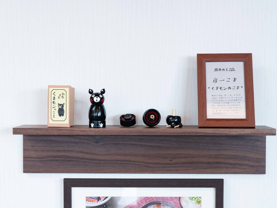 A wooden shelf with various items including a framed certificate, a black bear figurine, a small black bowl, and a wooden box.