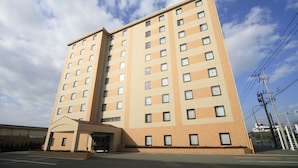 Un hotel de varios pisos con fachada color beige, ventanas grandes y un acceso cubierto.