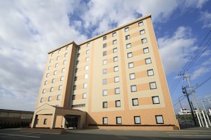 A multi-story hotel with a beige facade, large windows, and a covered entrance.