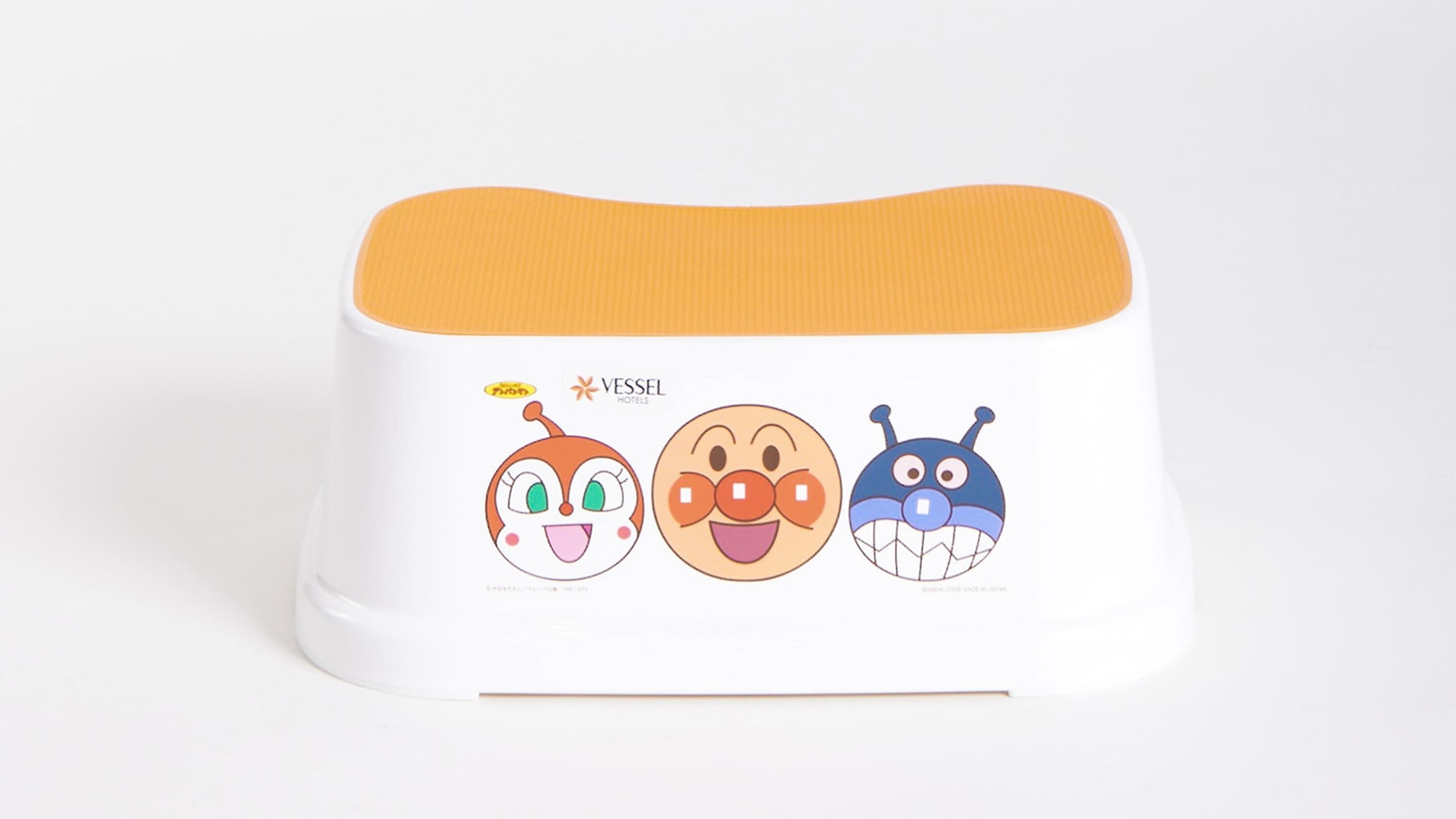 Un recipiente blanco y redondeado con tapa naranja y tres personajes de dibujos animados.