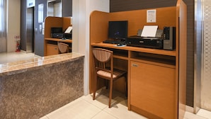 Een hotel receptie met een marmeren balie, een houten bureau, een computer, een printer en een brandblusser.