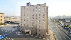 Een hotel met meerdere verdiepingen, een platte gevel, een parkeerplaats en uitzicht op de straat.
