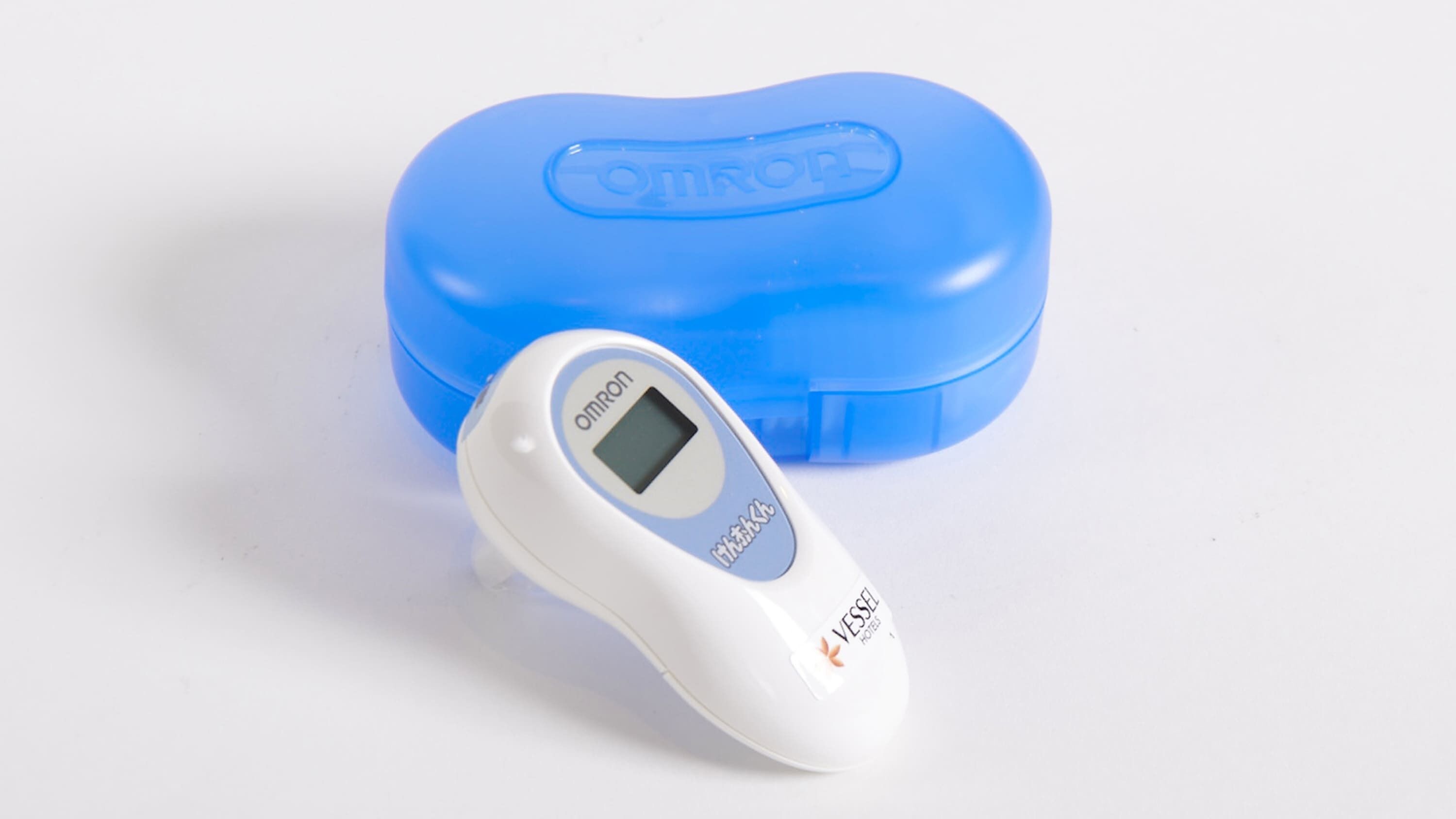 A white digital thermometer with a display screen and a blue case with the brand name "OMRON" embossed on it.
