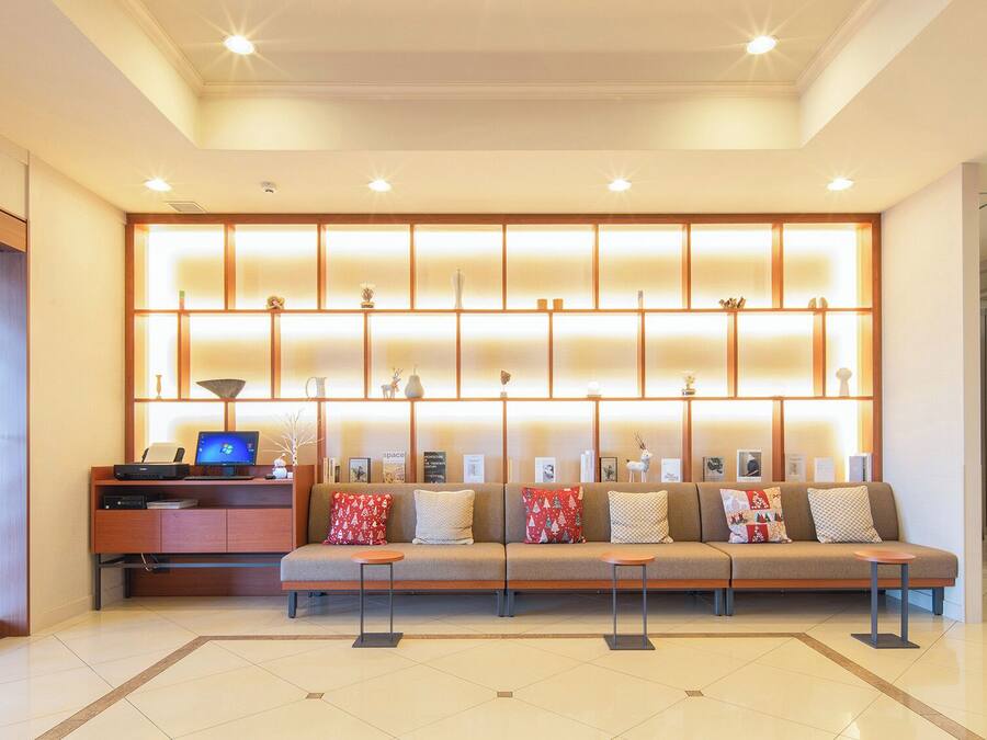 A modern lobby with a sofa, a desk with a computer, and a decorative wall.