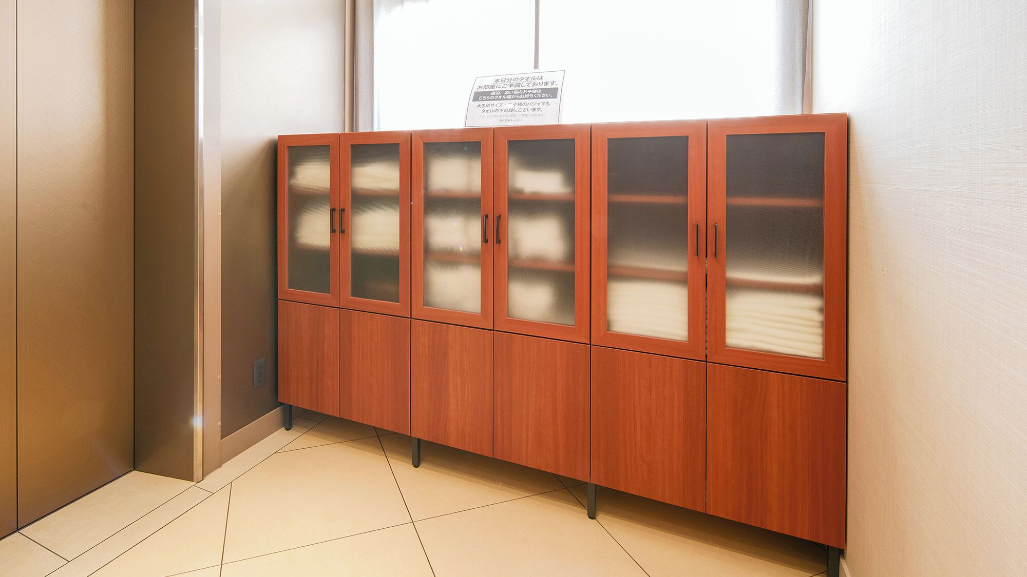 Un mueble de madera con puertas de cristal en un pasillo.
