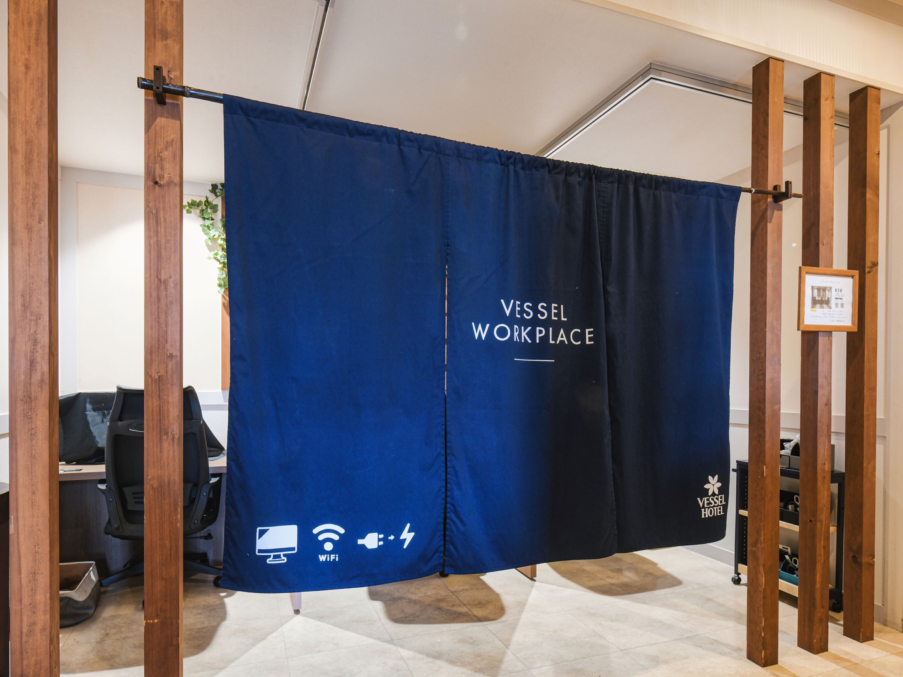 A blue curtain with "Vessel Workplace" and WiFi symbols, indicating a work area in a hotel.