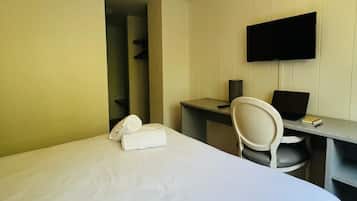 A hotel room with a bed, a desk with a chair, a flat-screen TV, and a telephone.