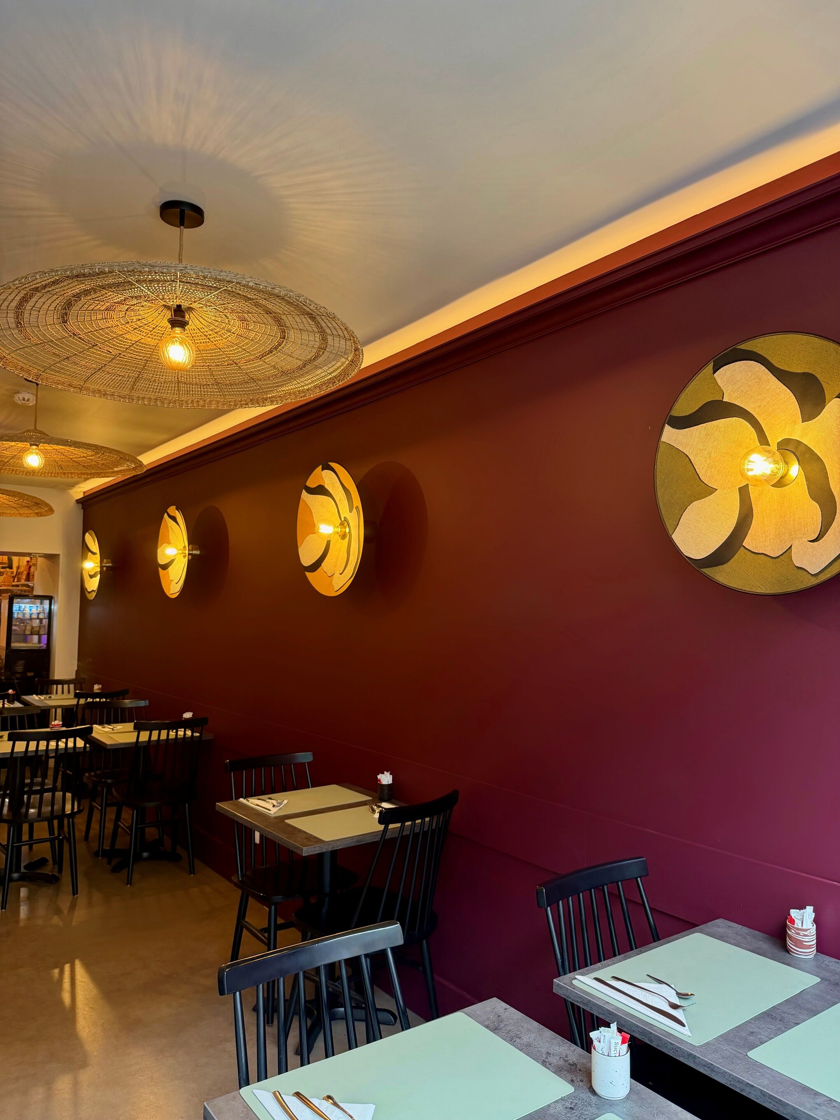 A restaurant interior with round tables, chairs, and decorative wall sconces.