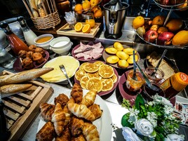 Un bufé de desayuno con diversas opciones de comida, incluyendo pasteles, frutas y bebidas.