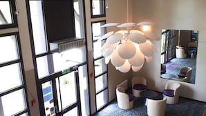 A modern interior with large windows, a unique spherical light fixture, and a seating area with white and purple chairs.