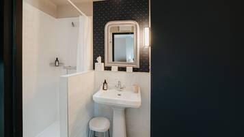 Un baño con un lavamanos blanco, un espejo y una ducha.