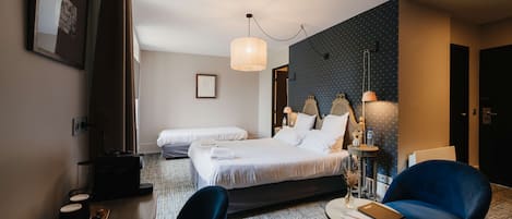 Una habitación de hotel con dos camas, un escritorio con silla, una mesita y una lámpara.