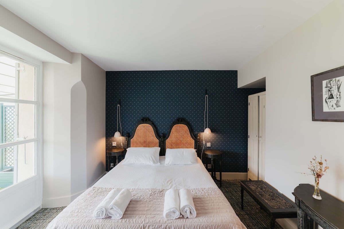 Une chambre d’hôtel avec un grand lit, deux tables de chevet, un banc et un bureau.