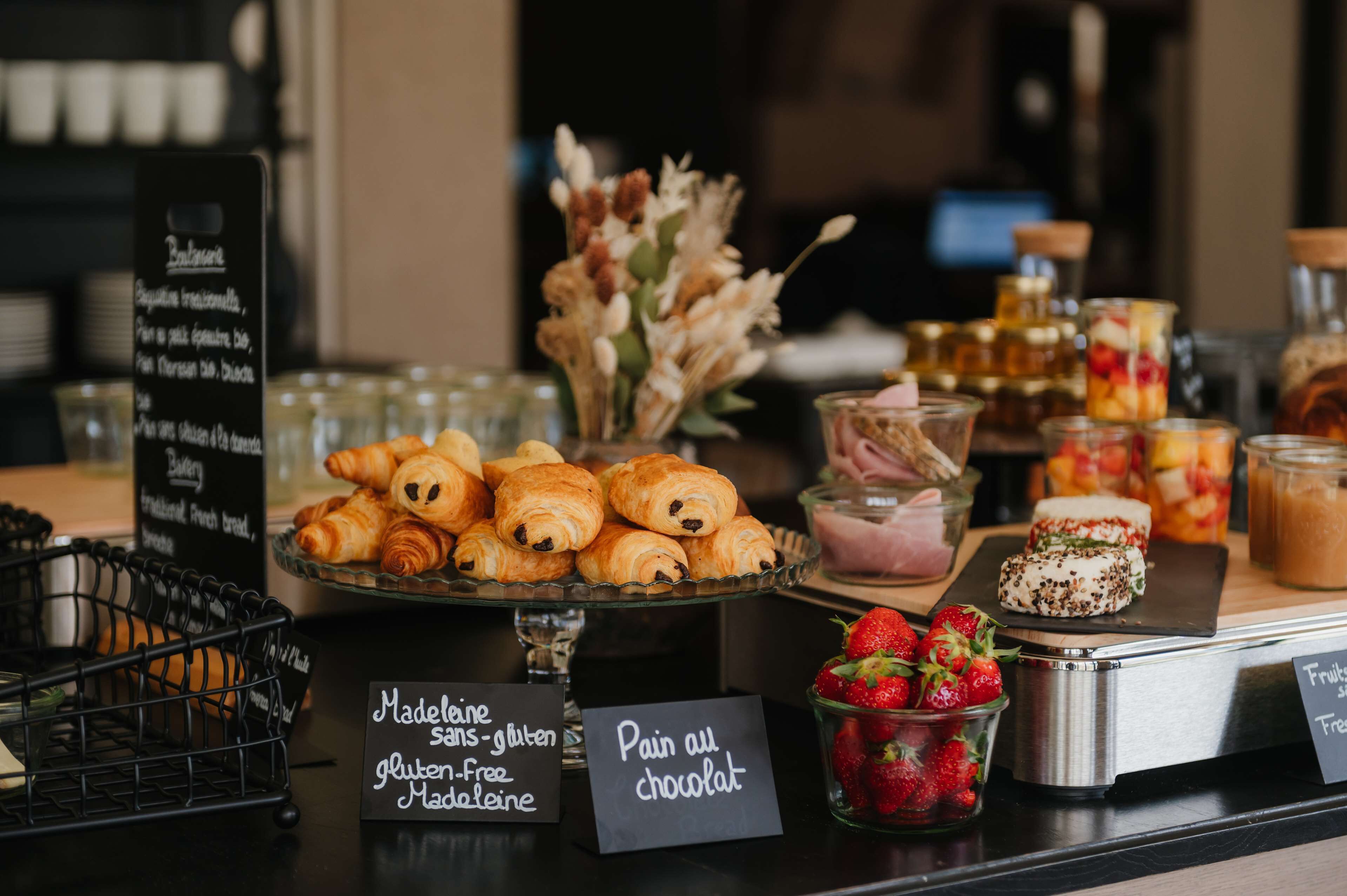A bakery display with various pastries, including gluten-free options, and fresh strawberries.