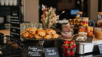 A bakery display with various pastries, including gluten-free options, and fresh strawberries.