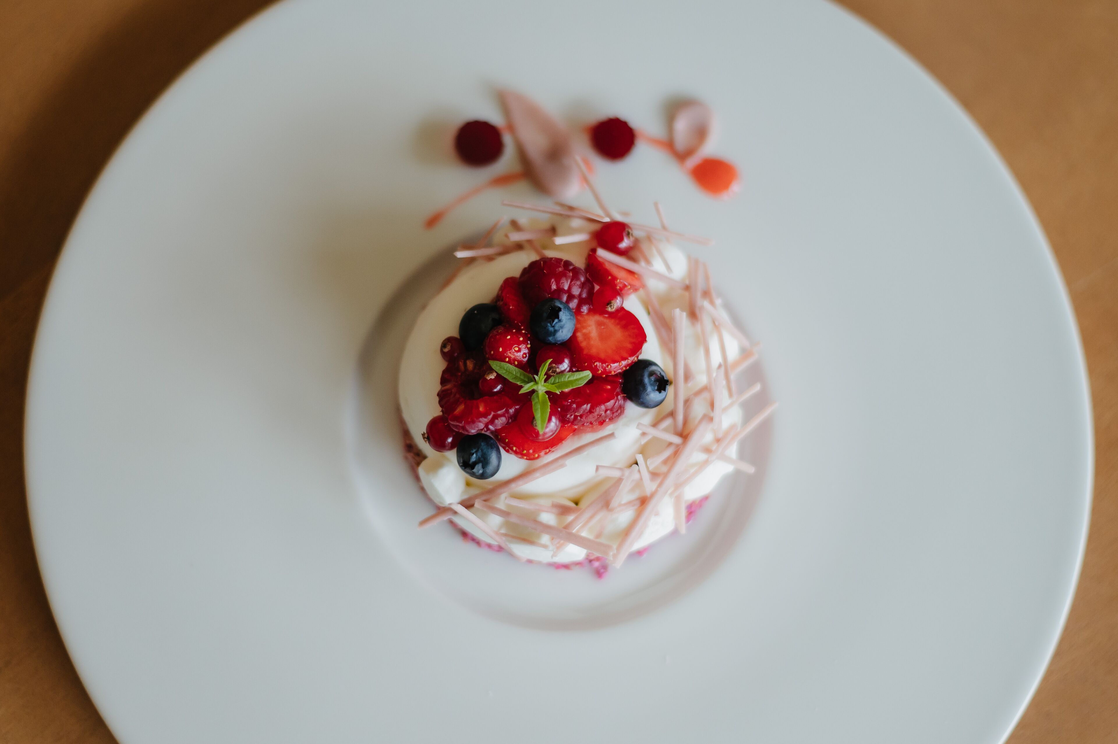 Dessert auf einem weißen Teller mit Erdbeeren, Blaubeeren und einem Klecks Sahne.