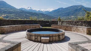 A hot tub in a wooden deck with a mountainous backdrop. - Hotel La Robeyere, BW Signature Collection (Embrun)