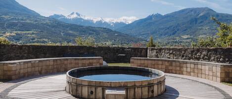 A hot tub in a wooden deck with a mountainous backdrop.