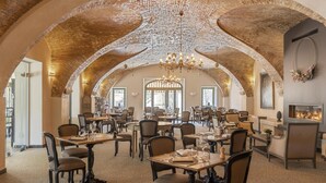 A spacious dining area with high arched ceilings and chandeliers, featuring multiple tables and chairs. - Hotel La Robeyere, BW Signature Collection (Embrun)
