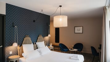 Ein Hotelzimmer mit einem Bett, zwei Sesseln, einem kleinen Tisch, einer Lampe und einer Wand mit Punkten.
