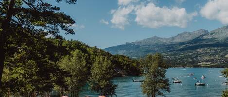 A lakeside view with boats, picnic tables, and umbrellas.
