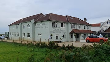 Un bâtiment à deux étages, sur lequel on peut lire une enseigne indiquant qu’il s’agit d’un DORMY HOUSE, restaurant, bar et hôtel.