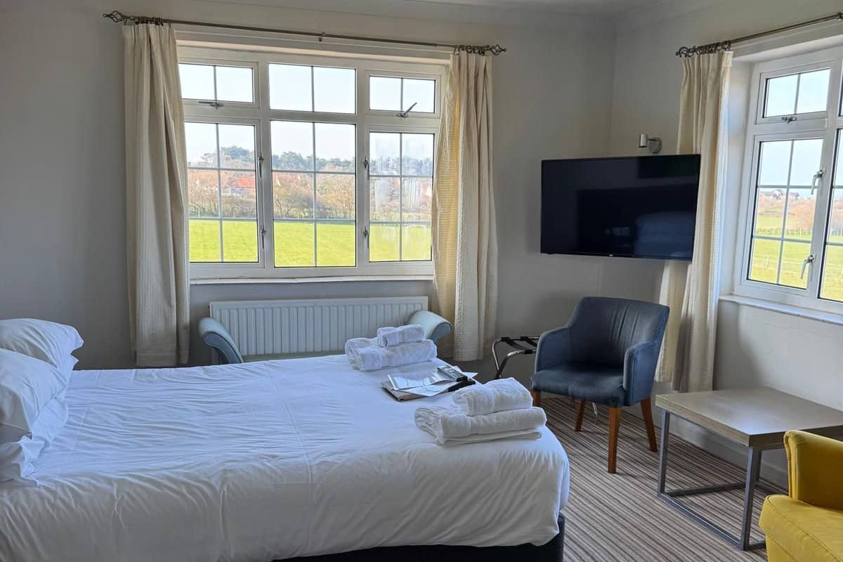 A hotel room with a large bed, a TV, a desk, and two chairs.