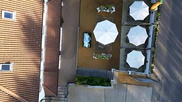 An aerial view of a patio area with outdoor seating, umbrellas, and a small water feature.