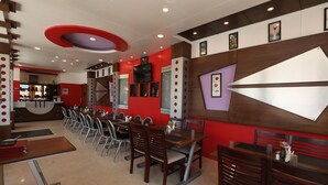 A restaurant with a long counter, multiple tables, and chairs. - Hotel Silver Oak (Ootacamund)