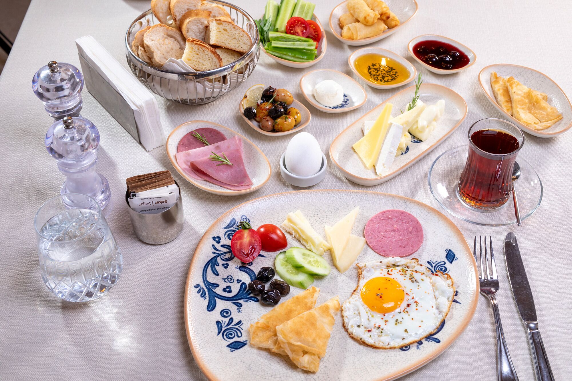 Una mesa de desayuno con diversos alimentos, como pan, huevos, queso y verduras.