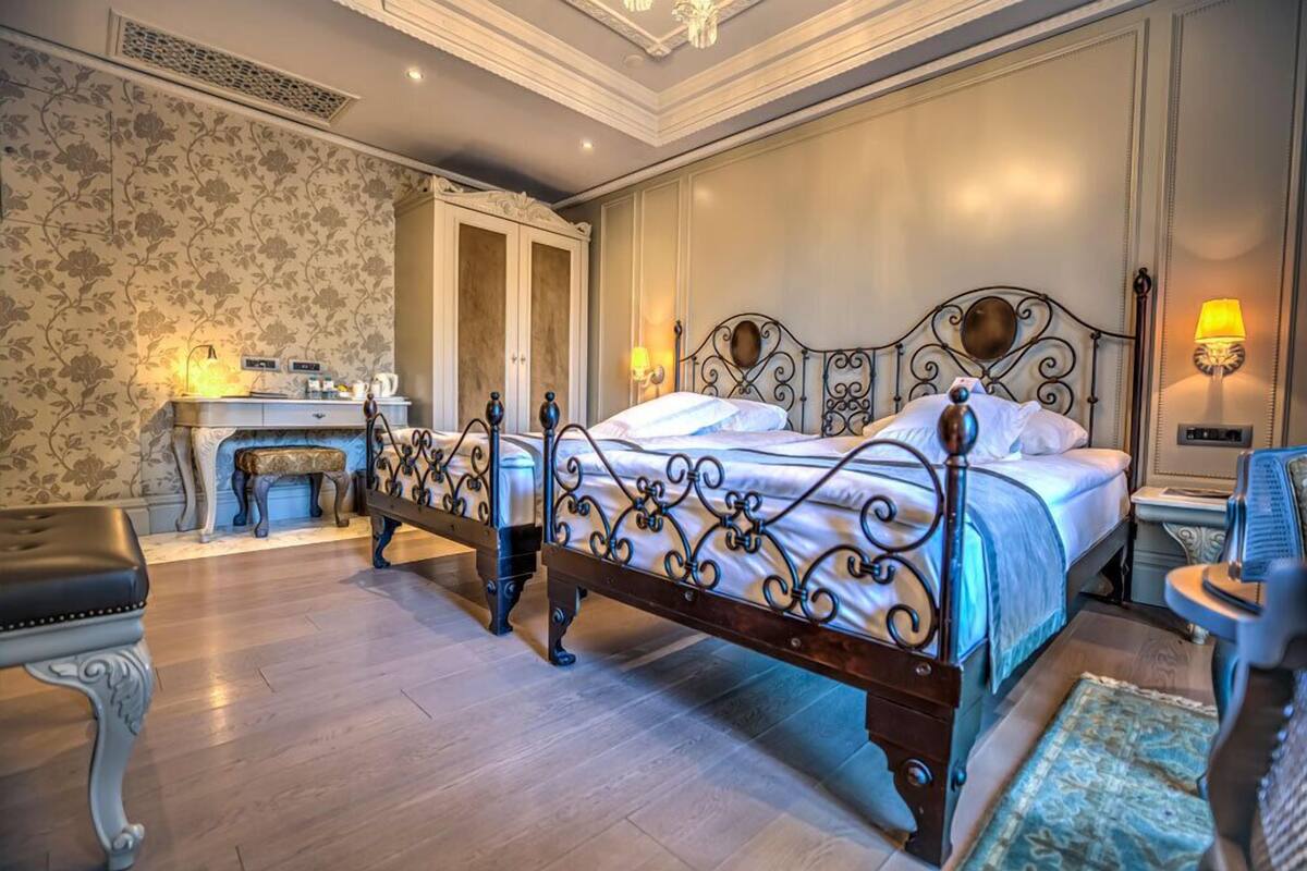 A bedroom with a large bed, a bedside table, a chair, a desk, and a wardrobe.