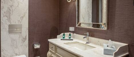 Un baño con tocador de mármol, un espejo grande y un inodoro.