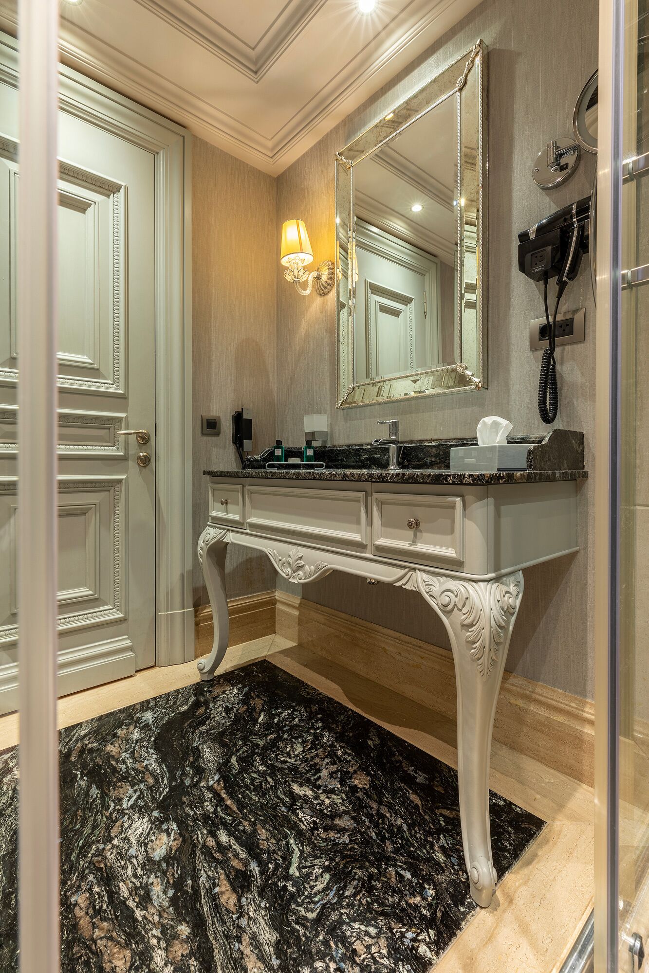 A bathroom with a large mirror, vanity, and a hairdryer on the wall.