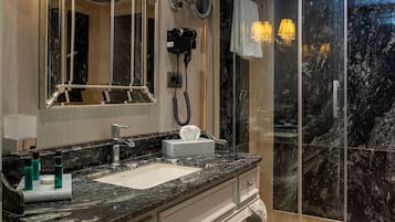 A luxurious bathroom with a marble sink, a large mirror, and a glass shower enclosure.