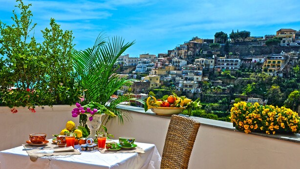 Una mesa lista para el desayuno con vistas a un pueblo en la ladera.
