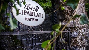Un letrero con la inscripción 'B&B LIPARLATI POSITANO', sujeto a una reja metálica con detalles decorativos en forma de volutas.