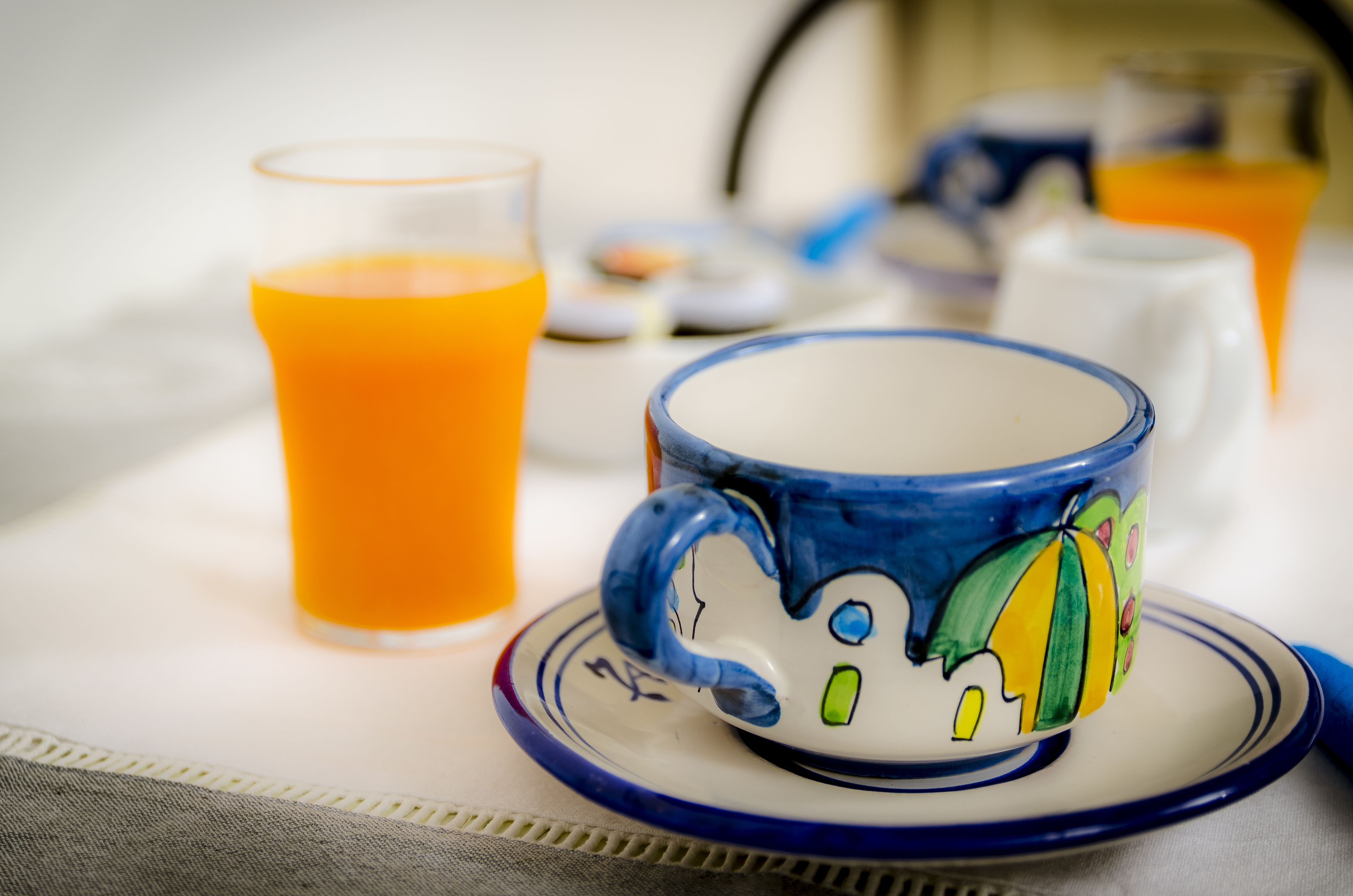 Un desayuno con una taza de cerámica, un vaso de jugo de naranja y un plato blanco.