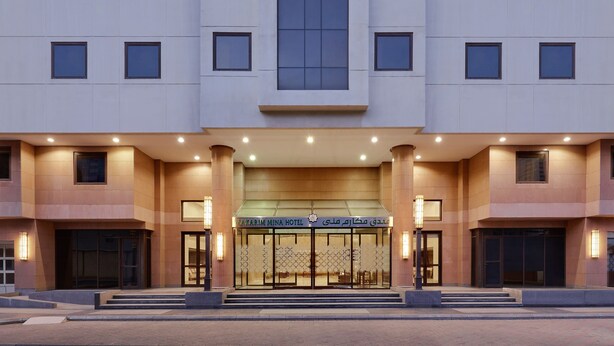 Ein modernes Hotel mit einer symmetrischen Fassade, großen Fenstern und einem markanten Eingang mit Stufen zu den Türen.