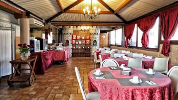 A restaurant with round tables covered in red tablecloths, white chairs, and a wooden ceiling with exposed beams.