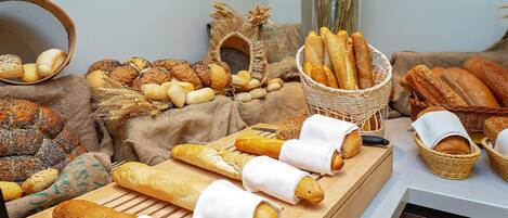 Verschiedene Brotsorten und Gebäck auf einem Holzboden, mit Körben und einem gewebten Korb im Hintergrund.