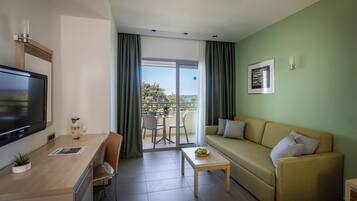 Una habitación de hotel moderna con sofá, televisor, mesa de comedor y balcón con vistas.