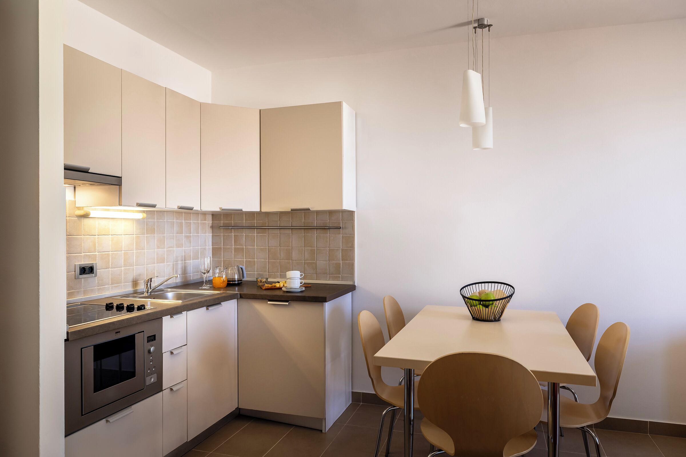A modern kitchen with a built-in oven, a sink, and a dining area with a table and chairs.