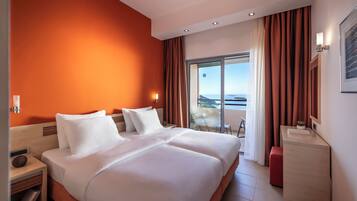 A modern hotel room with a large bed, a desk, and a view of the outdoors.