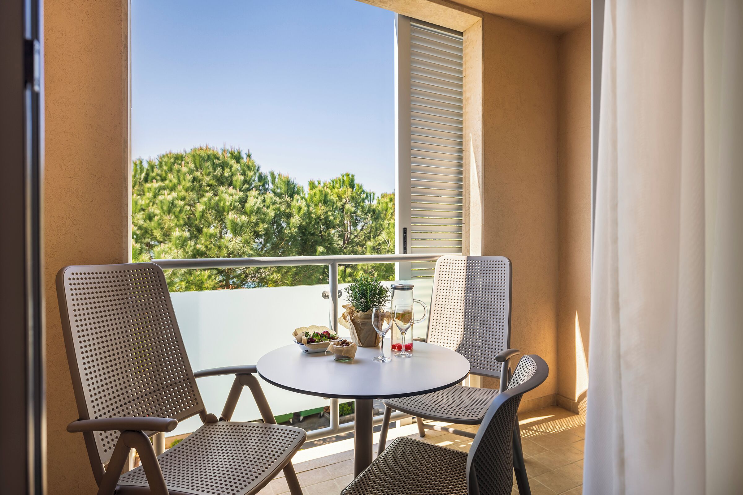 A balcony with two wicker chairs, a small round table, and a potted plant.