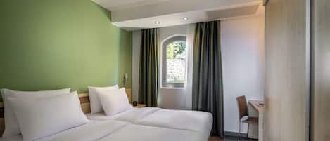 A hotel room with a bed, a desk, and a chair.