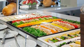 Un bufé con diversas opciones de comida, incluyendo ensaladas, carnes y vegetales.