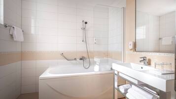 A modern bathroom with a freestanding bathtub, a glass-enclosed shower, and a vanity with a sink and mirror.